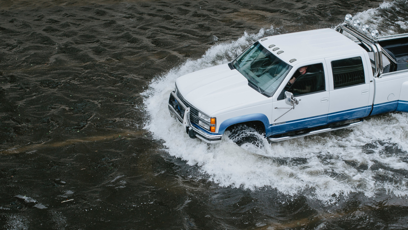 A man drives his truck through flooded downtown Jacksonville, Florida, streets. - Unsplash