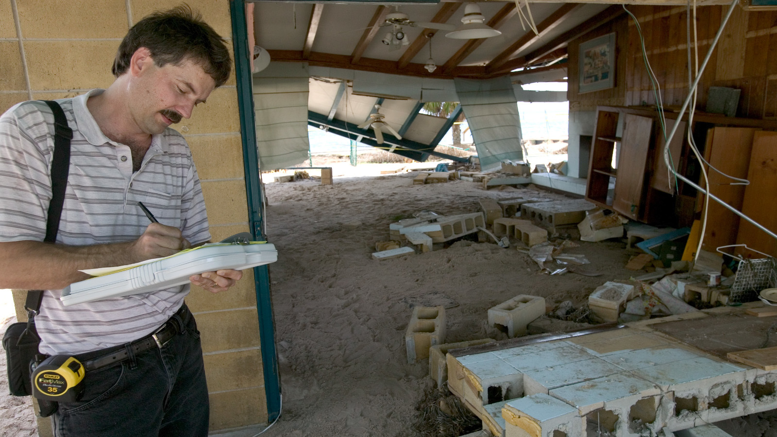 Insurance adjuster Mike McConaghy reviews the remains of a home at Shell Point, Florida, following Hurricane Dennis in July 2005. - FEMA
